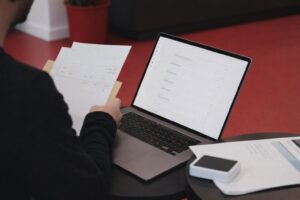 En person granskar en faktura framför en laptop på ett kontor.